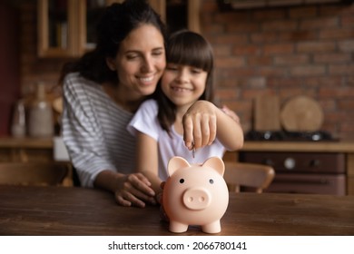 Happy Mom Teaching Smart Daughter Girl To Save Invest Money, Motivate Child For Accounting, Investment, Planning Future. Kid Dropping Cash Into Pink Piggy Bank. Family Economy. Close Up