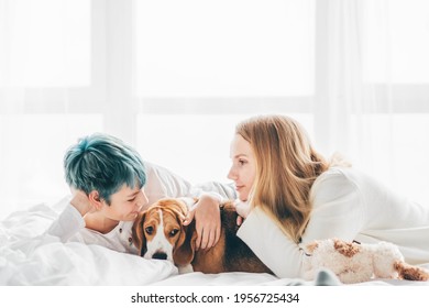 Happy Mom And Teenage Son, Parent And Child Laying At Home With Pet Little Dog, Real Friendly Loving Family. 