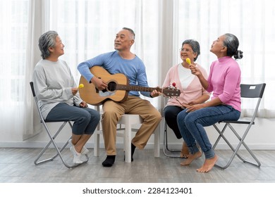 Happy moment with Group of Asian senior man playing guitar and woman singing and dance with fun togetherness in living room at nursing home - Powered by Shutterstock