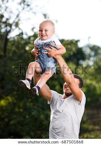 Happy moments. Father throws up his son in the sky at sunset in nature.