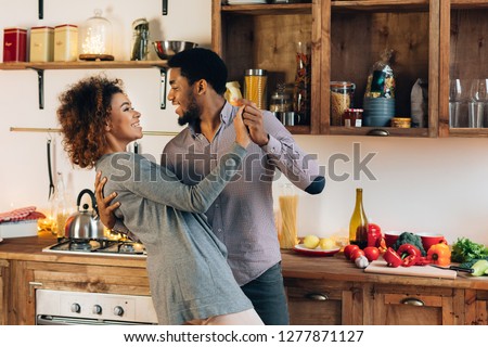 Happy moments. Young african-american couple in love dancing in kitchen, copy space