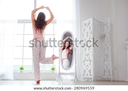 Happy morning. Attractive young woman dancing near mirror at her apartment.