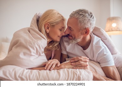 Guten Morgen! Ehepaar mittleren Alters mit romantischer Atmosphäre im Schlafzimmer