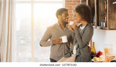 Happy morning together. Cute young african-american couple drinking coffee in cozy kitchen, panorama, copy space - Powered by Shutterstock