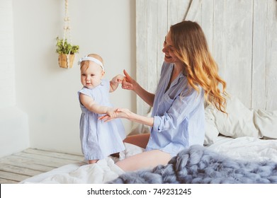 Happy Mother And 9 Month Old Baby In Matching Pajamas Playing In Bedroom In The Morning. Cozy Family Weekend.