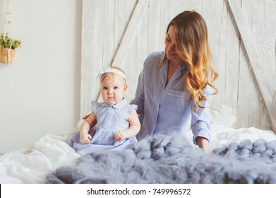 Happy Mother And 9 Month Old Baby In Matching Pajamas Playing In Bedroom In The Morning. Cozy Family Weekend.