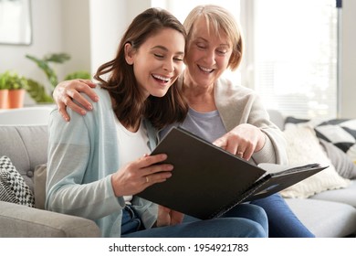 Happy mother and adult daughter looking photo album - Powered by Shutterstock