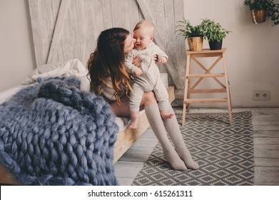 Happy Mother And Baby Playing At Home In Bedroom. Cozy Family Lifestyle In Modern Scandinavian Interior. 