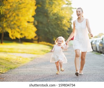 Happy Mother And Baby Walking In City