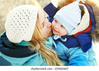 Happy Mother And Baby In Winter Park. Family Outdoors. Cheerful Mommy With Her Child