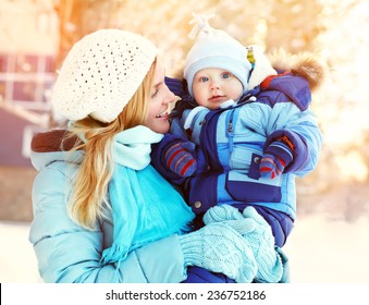 Happy Mother And Baby In Winter Park. Family Outdoors. Cheerful Mommy With Her Child