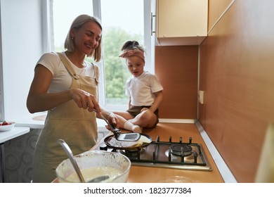 happy mother baking with little daughter in apron and cook hat working with flour , bowl and spoon preparing dough teaching the kid baking and having fun together. - Powered by Shutterstock