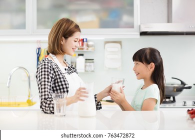 Happy Mother And Child In Kitchen Drinking Milk