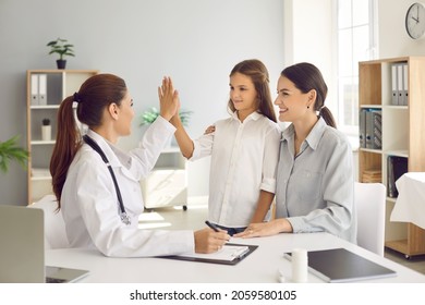 Happy Mother And Child Seeing Their Family Doctor At The Hospital. Female Pediatrician Or General Practitioner Giving A Five To A Little Girl. Trust, Support, Good Relationship With Patients Concept