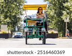 A happy mother and child share a joyful bicycle ride through the scenic streets of Waterton, Alberta on a bright, sunny day.