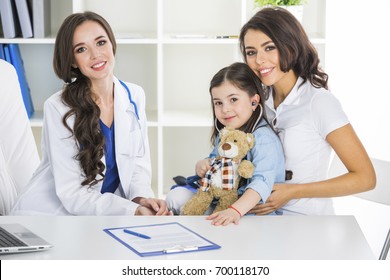 Happy Mother And Child With Teddy Bear And Stethoscope At Pediatrician Office