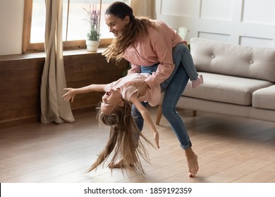 Happy mother circling little daughter in dance, active mommy her preschool funny kid girl dancer having fun listen funky music enjoy playtime on weekend at home. Hobby activity, leisure time concept