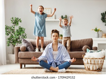 Happy mother with closed eyes meditating in lotus pose on floor trying to save inner harmony while excited children jumping on sofa and screaming in light spacious living room
 - Powered by Shutterstock