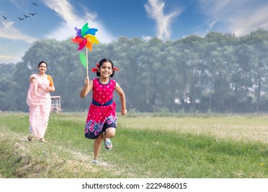 Happy mother with cute little girl running carefree and having fun with colorful pin wheel.