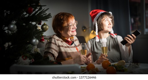 Happy Mother And Daughter Drink Champagne And Watch TV On Christmas Night