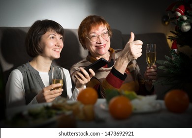 Happy Mother And Daughter Drink Champagne And Watch TV On Christmas Night