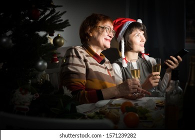 Happy Mother And Daughter Drink Champagne And Watch TV On Christmas Night