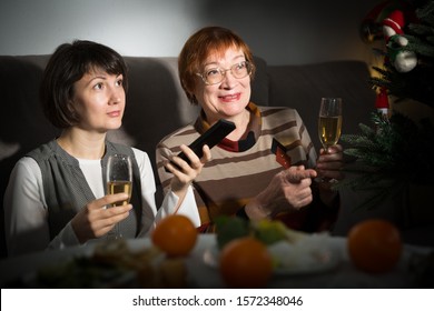 Happy Mother And Daughter Drink Champagne And Watch TV On Christmas Night