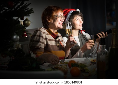 Happy Mother And Daughter Drink Champagne And Watch TV On Christmas Night. High Quality Photo