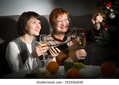 Happy Mother And Daughter Drink Champagne And Watch TV On Christmas Night. High Quality Photo