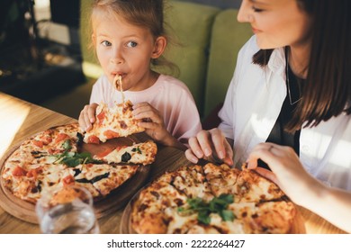 Happy mother and daughter eat pizza in a cafe and having fun. - Powered by Shutterstock