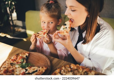 Happy mother and daughter eat pizza in a cafe and having fun. - Powered by Shutterstock