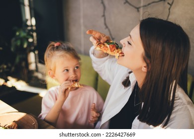 Happy mother and daughter eat pizza in a cafe and having fun. - Powered by Shutterstock