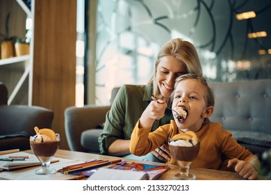 Happy Mother And Daughter Enjoying In Dessert At Home. Ficus Is On Girl Eating Chocolate Mousse.