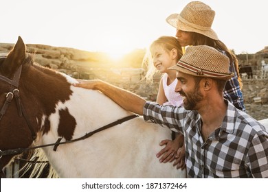 Happy mother daughter and father family having fun riding horse inside ranch