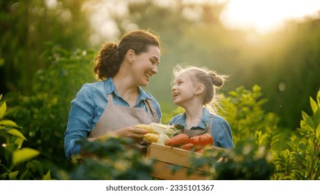 Happy mother and daughter gardening in the backyard organic garden. Kid and mom picking fresh vegetables and learning botany.  - Powered by Shutterstock