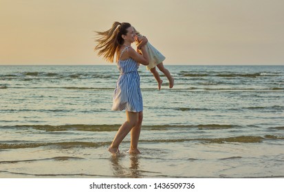 Happy mother and daughter have fun on the beach at sunset time. - Shutterstock ID 1436509736