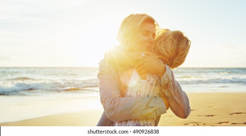 Happy mother and daughter having fun playing on the beach at sunset