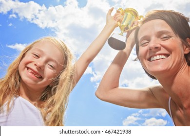 Happy Mother And Daughter Holding A Trophy High Up