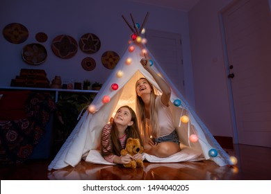 Happy Mother And Daughter Inside Tepee Tent In Bedroom, Looking And Pointing Ceiling Counting Stars; Family Relationship Concept.