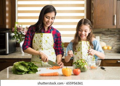 Happy Mother And Daughter Making A Salad For Dinner Together At Home