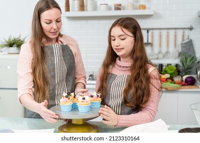 Happy Mother And Daughter Preparing And Decorating Homemade Cake In The Kitchen. Mom Teaching Little Girl Baking Bakery. Family Activity At Home