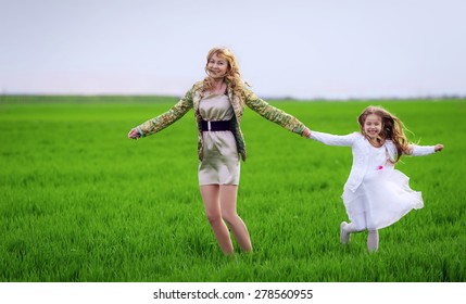 Happy mother and daughter run on the meadow