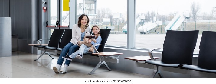 Happy Mother And Daughter Sitting In Airport Lounge Hall, Banner