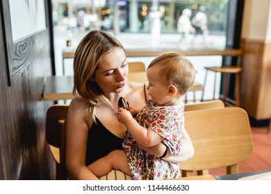 Happy mother and daughter are sitting and playing in the cafe.