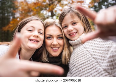 Happy mother daughters selfie portrait in the wood, enjoying time together in the nature and taking a photo smiling at camera and making a frame with hands - Lifestyle and family concepts - Powered by Shutterstock