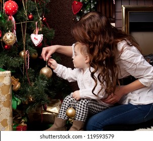 Happy mother decorating christmas tree with her baby