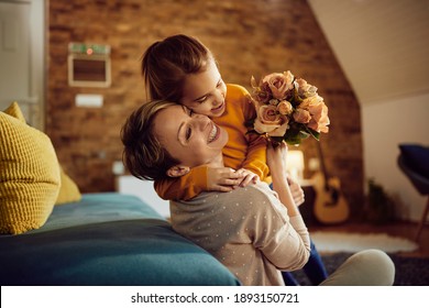 Feliz madre abrazando a su hija mientras recibe un ramo de flores en casa.  Foto de stock