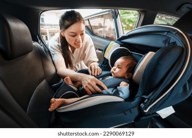 happy mother is fastening safety belt to newborn baby in the car seat - Shutterstock ID 2290069129