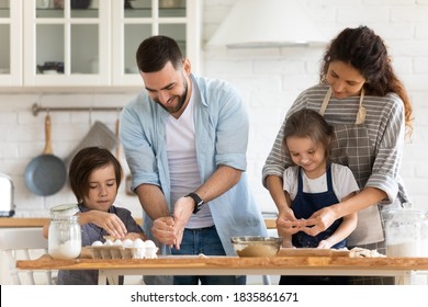 Happy mother and father with two kids baking together, standing at wooden countertop in modern kitchen, young parents with little daughter and son cooking pastry or pie, enjoying leisure time - Shutterstock ID 1835861671