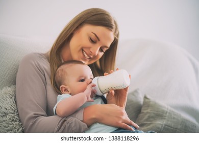 Happy mother is feeding her baby boy at home. - Powered by Shutterstock